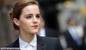 A color photograph of Emma Watson smiling at the camera, exuding confidence and elegance.